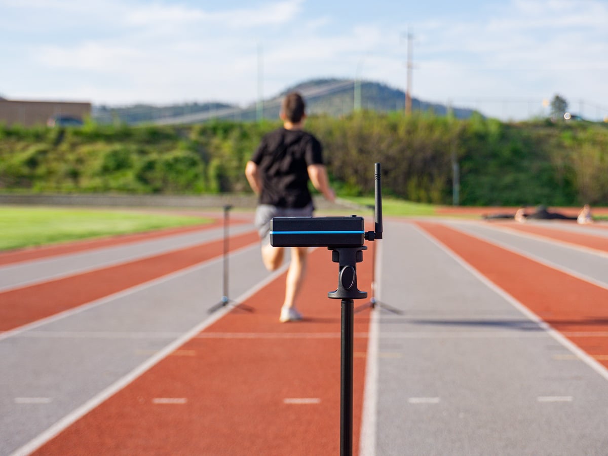 Sprinter running a flying 10 through two gates on a track.