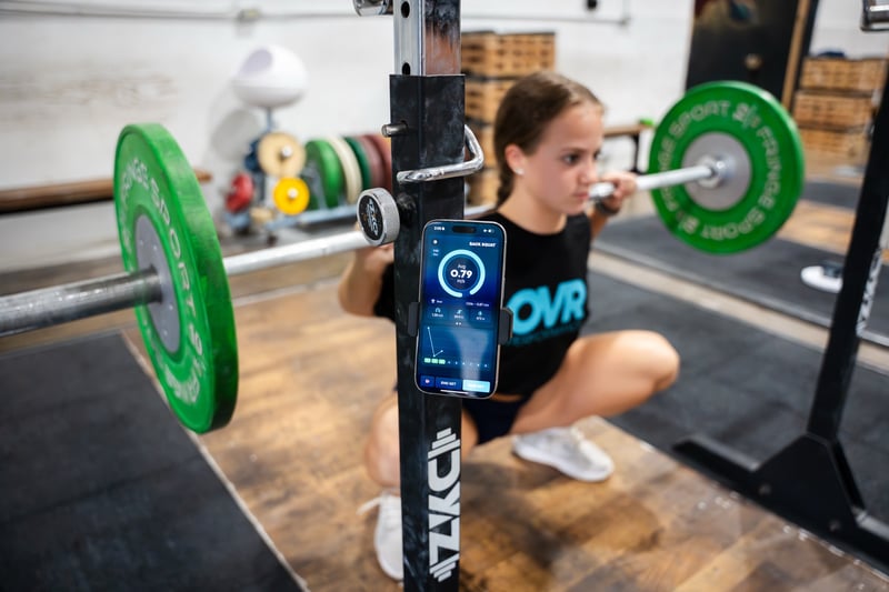 Athlete back squatting while OVR Velocity tracks bar speed